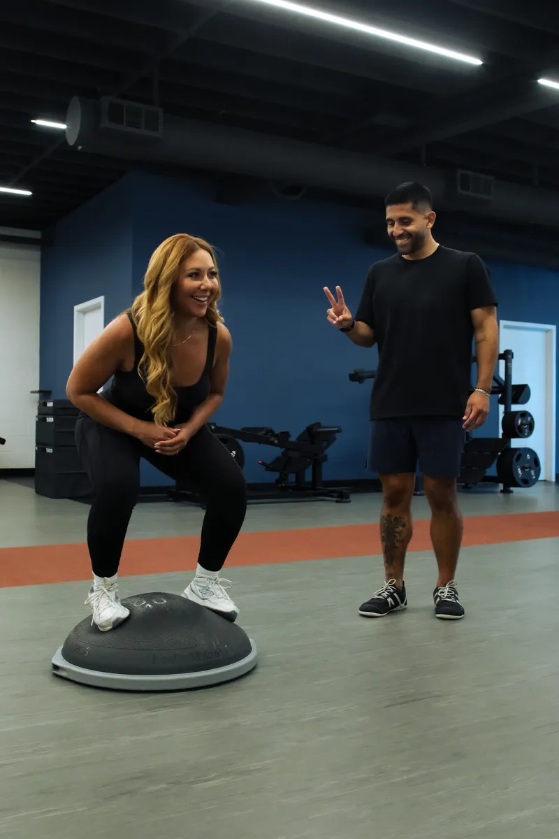 Balance squat on a BOSU trainer with coach support